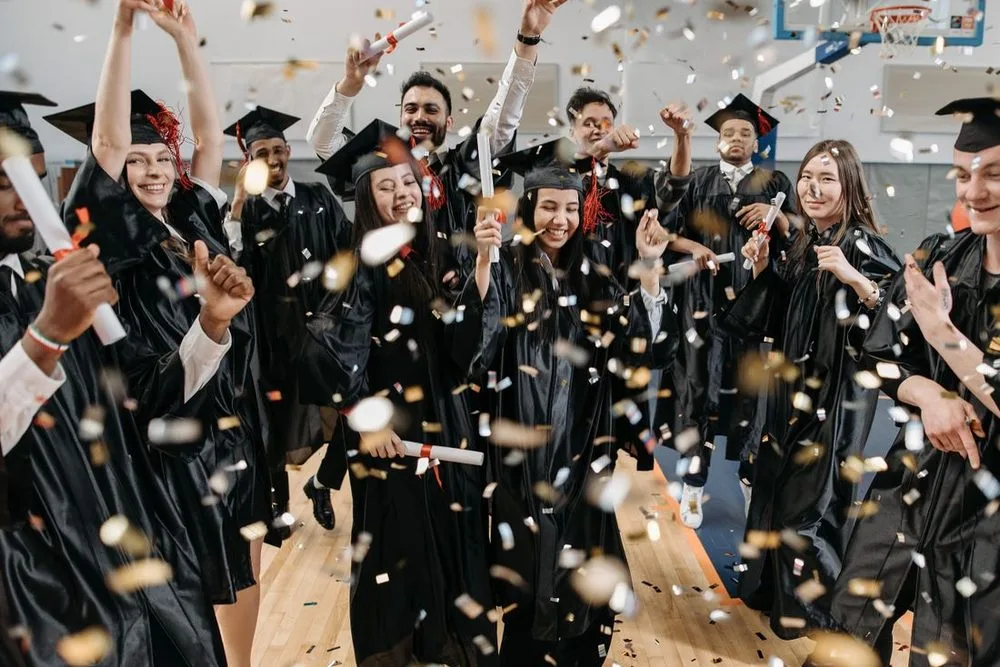 Graduates celebrating together in caps and gowns with confetti